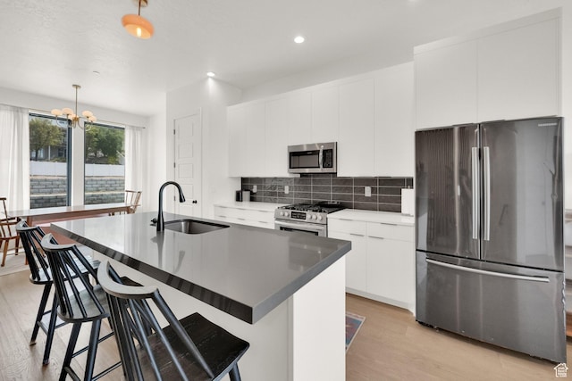 14348 S Champ Cv, Draper, UT 84020 - kitchen featuring backsplash, appliances with stainless steel finishes, a sink, light wood-style floors, and an island with sink