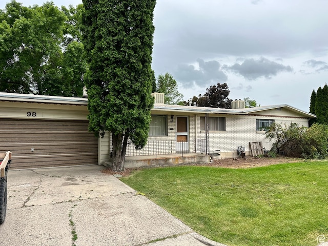 single story home with a porch, driveway, brick siding, a front lawn, and an attached garage