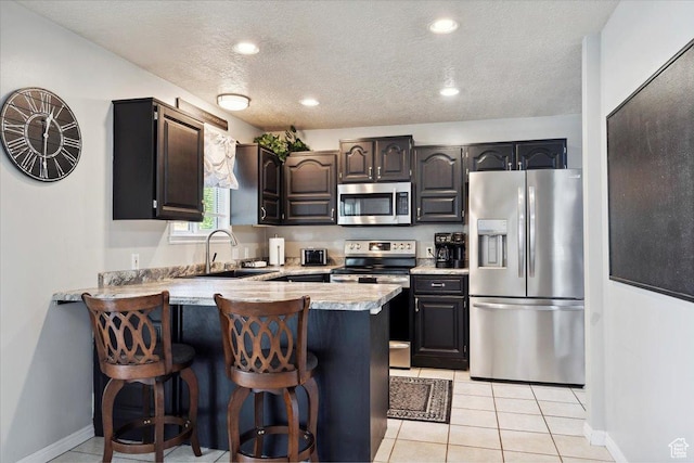 121 N 3000 W, West Point, UT 84015 - kitchen featuring appliances with stainless steel finishes, a sink, light countertops, a peninsula, and a breakfast bar