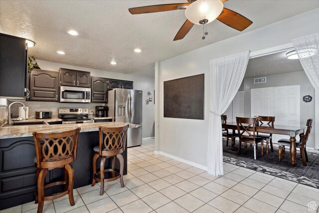 121 N 3000 W, West Point, UT 84015 - kitchen with appliances with stainless steel finishes, a sink, light tile patterned floors, light countertops, and a peninsula