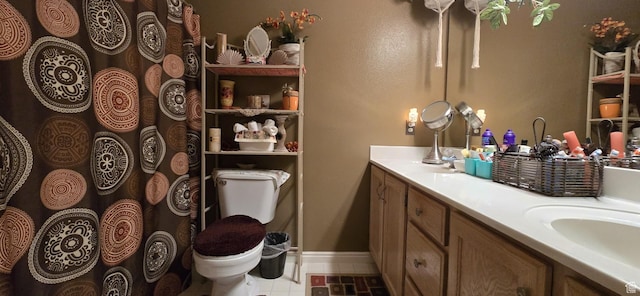 full bath with baseboards, double vanity, a sink, and toilet