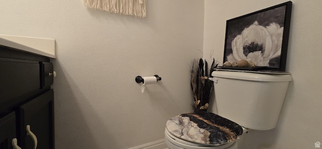 half bath featuring toilet, baseboards, and vanity