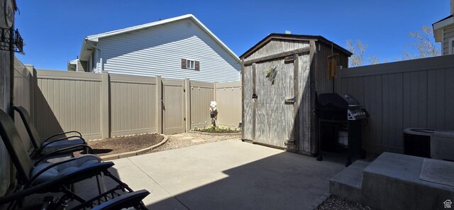 view of patio with a fenced backyard, a storage unit, an outbuilding, and area for grilling