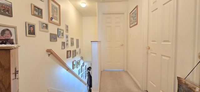 hallway with carpet flooring, baseboards, and an upstairs landing