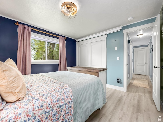 bedroom with a textured ceiling, baseboards, and light wood-style floors