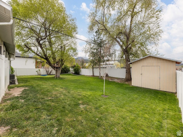 view of yard featuring a storage shed, an outbuilding, and a fenced backyard