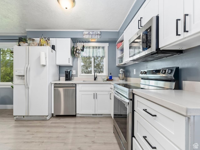 kitchen with stainless steel appliances, a textured ceiling, plenty of natural light, and a sink