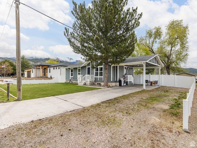 ranch-style home with fence, a shingled roof, a front lawn, a carport, and driveway