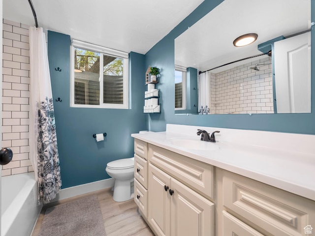 full bath featuring wood finished floors, baseboards, vanity, toilet, and shower / tub combo with curtain