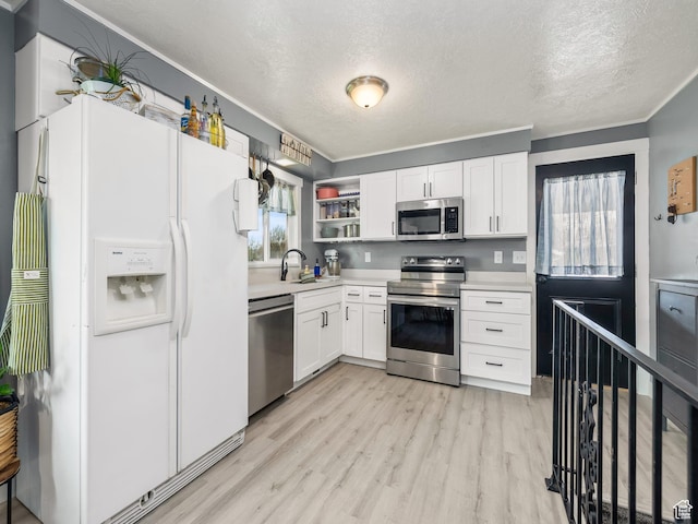 kitchen with light wood-style floors, a sink, appliances with stainless steel finishes, and light countertops