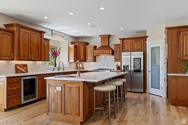 864 S Wellington Dr W, Kaysville, UT 84037 - kitchen featuring stainless steel fridge, beverage cooler, premium range hood, a center island with sink, and light wood-type flooring