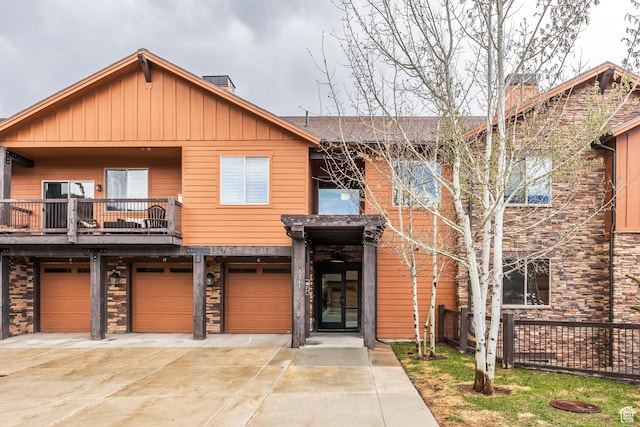 1261 W Black Rock Trl Unit 39F, Kamas, UT 84036 - view of front facade with board and batten siding, driveway, a chimney, a garage, and a balcony