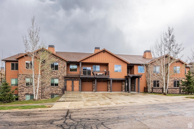 1261 W Black Rock Trl Unit 39F, Kamas, UT 84036 - view of front of house with an attached garage, stone siding, a chimney, concrete driveway, and a balcony