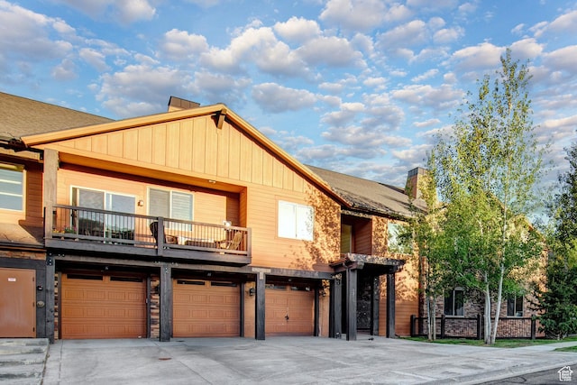 1261 W Black Rock Trl Unit 39F, Kamas, UT 84036 - view of front of home featuring board and batten siding, an attached garage, a balcony, driveway, and a chimney