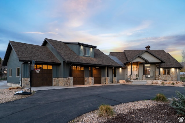 view of front facade featuring a porch, roof with shingles, aphalt driveway, an attached garage, and stone siding