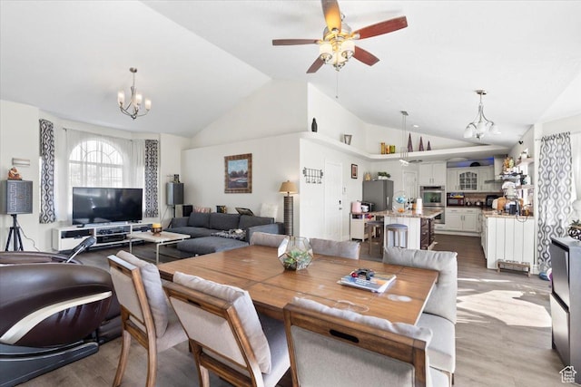 6268 S Faber Ln, Taylorsville, UT 84123 - dining room featuring ceiling fan with notable chandelier, vaulted ceiling, and wood finished floors