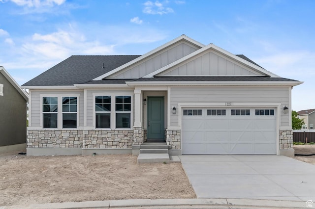 craftsman-style house with stone siding, board and batten siding, concrete driveway, and a shingled roof