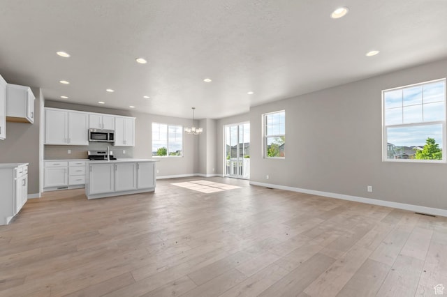 kitchen featuring appliances with stainless steel finishes, a chandelier, baseboards, open floor plan, and recessed lighting