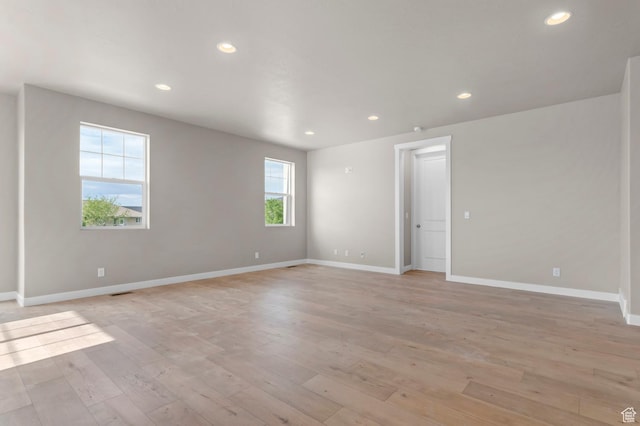 empty room with light wood-type flooring, baseboards, and recessed lighting