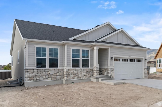 craftsman-style home with stone siding, board and batten siding, driveway, an attached garage, and a shingled roof