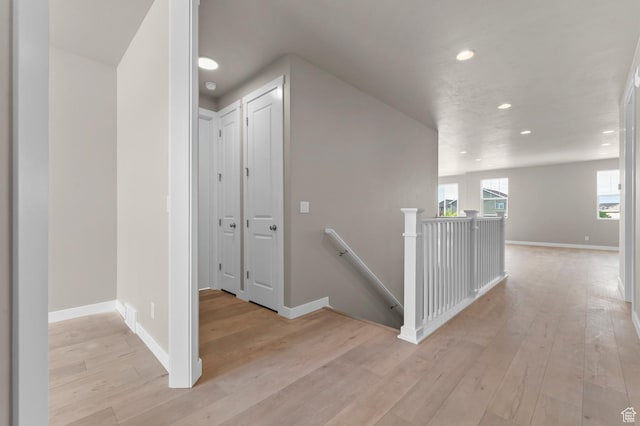 corridor featuring an upstairs landing, recessed lighting, light wood-style flooring, and baseboards