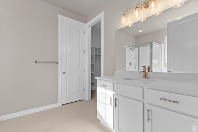 bathroom with a shower stall, tile patterned floors, vanity, baseboards, and a walk in closet