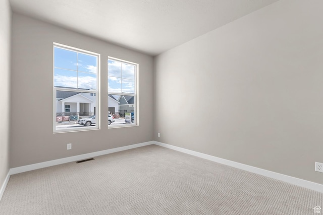 spare room with light colored carpet and baseboards