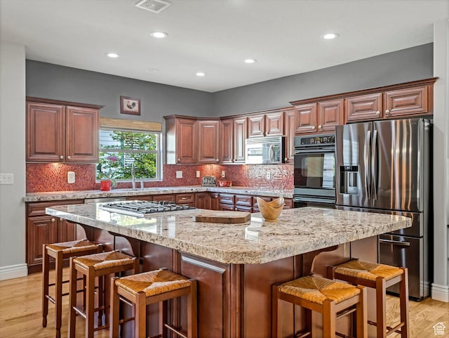 11606 S Radience Ln W, South Jordan, UT 84009 - kitchen with light wood-type flooring, backsplash, a kitchen bar, and stainless steel appliances
