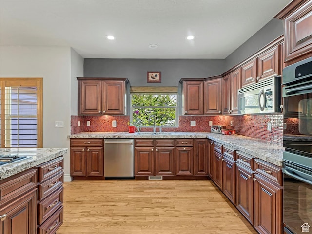 11606 S Radience Ln W, South Jordan, UT 84009 - kitchen featuring appliances with stainless steel finishes, light stone counters, a sink, light wood finished floors, and decorative backsplash
