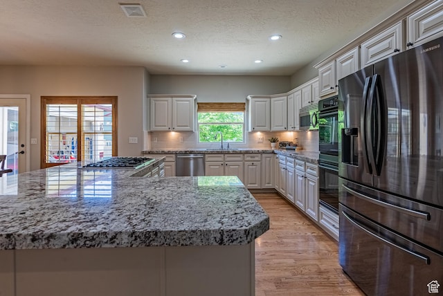 11606 S Radience Ln W, South Jordan, UT 84009 - kitchen with stainless steel appliances, light wood-style flooring, recessed lighting, tasteful backsplash, and light stone counters