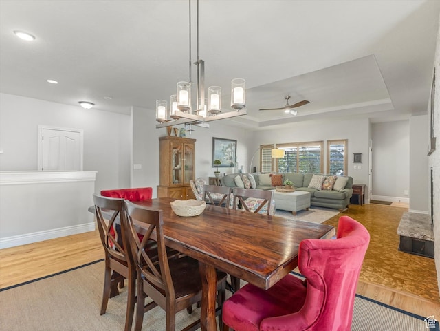 11606 S Radience Ln W, South Jordan, UT 84009 - dining space featuring baseboards, a raised ceiling, light wood-style floors, and ceiling fan with notable chandelier
