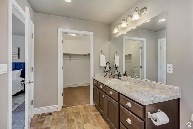 145 E Majestic Elms Pl S, South Salt Lake, UT 84115 - ensuite bathroom featuring connected bathroom, visible vents, wood finished floors, vanity, and a spacious closet