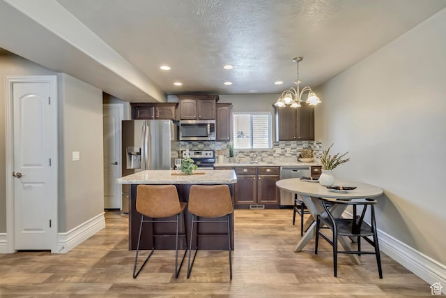 145 E Majestic Elms Pl S, South Salt Lake, UT 84115 - kitchen with baseboards, appliances with stainless steel finishes, dark brown cabinets, and a center island