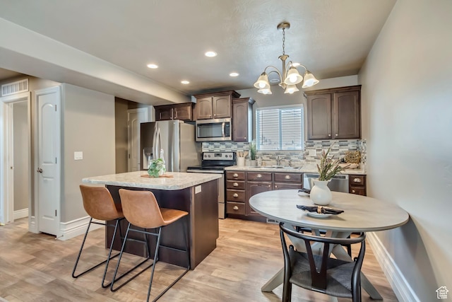 145 E Majestic Elms Pl S, South Salt Lake, UT 84115 - kitchen featuring dark brown cabinetry, baseboards, a center island, a sink, and appliances with stainless steel finishes
