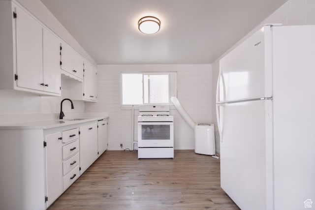 kitchen featuring a sink, light wood-style floors, white appliances, white cabinetry, and tile walls