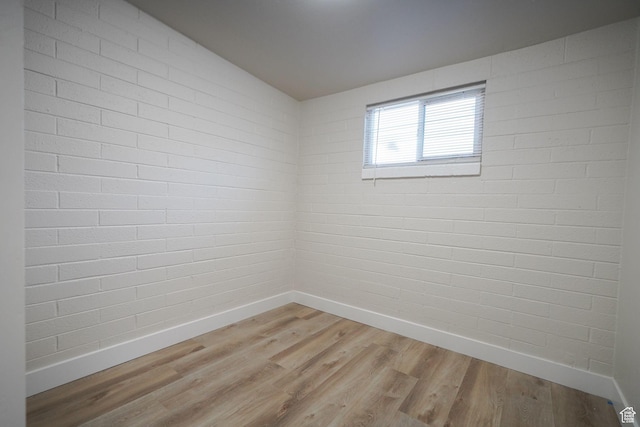 spare room with baseboards and light wood-style floors
