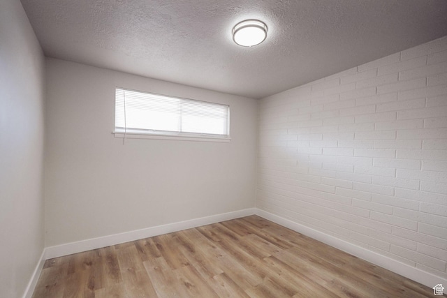 unfurnished room with a textured ceiling, baseboards, and light wood finished floors