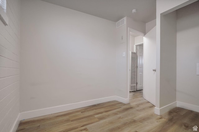 spare room with baseboards, visible vents, light wood-type flooring, and a heating unit