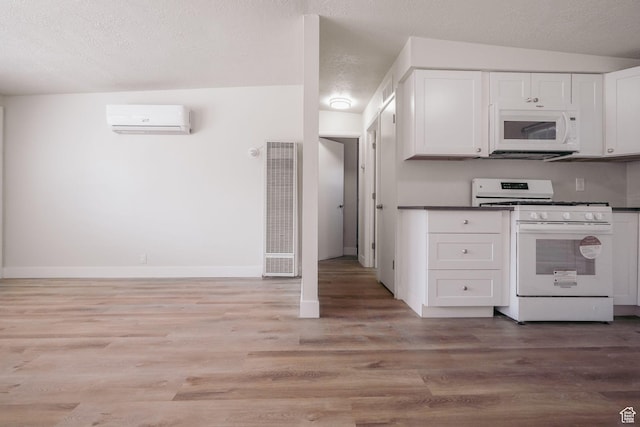 kitchen featuring light wood-type flooring, white cabinets, an AC wall unit, white appliances, and a heating unit
