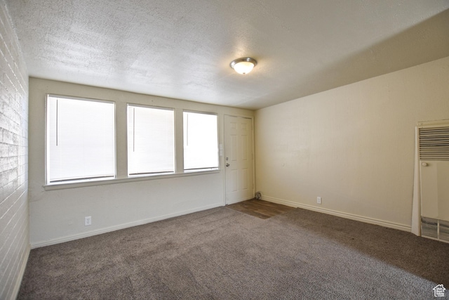 spare room featuring a textured ceiling, a heating unit, a wealth of natural light, and carpet