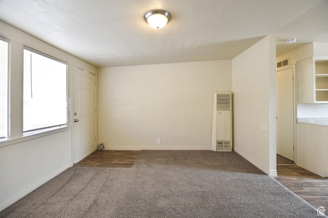 empty room with visible vents, a heating unit, carpet, and baseboards
