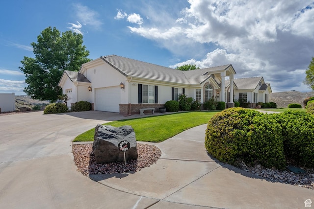 ranch-style home featuring a tiled roof, driveway, a front yard, an attached garage, and stucco siding