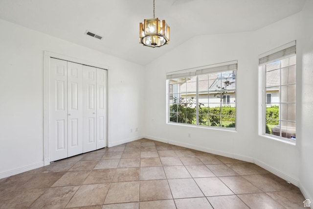 unfurnished bedroom featuring a notable chandelier, baseboards, lofted ceiling, visible vents, and a closet