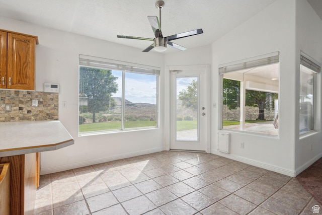 interior space with plenty of natural light, a ceiling fan, and baseboards