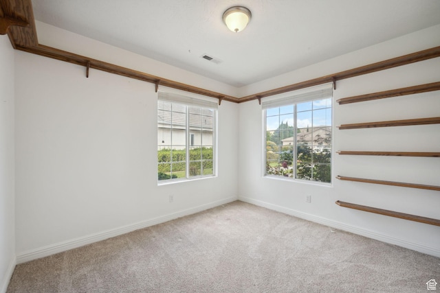 carpeted empty room with visible vents and baseboards