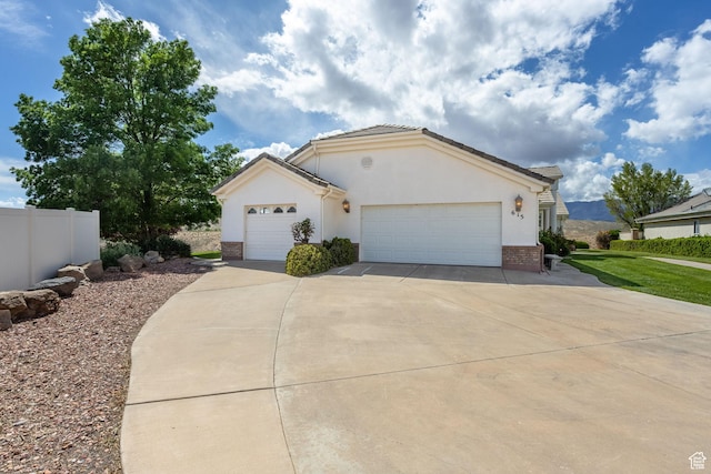 single story home with stucco siding, an attached garage, driveway, and brick siding