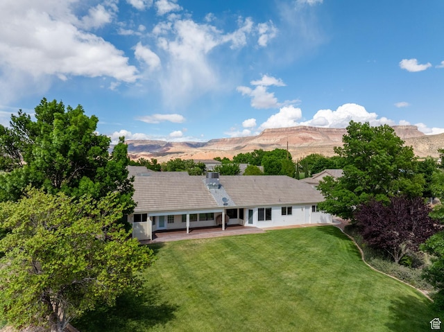 rear view of property with a yard, a patio, and a mountain view