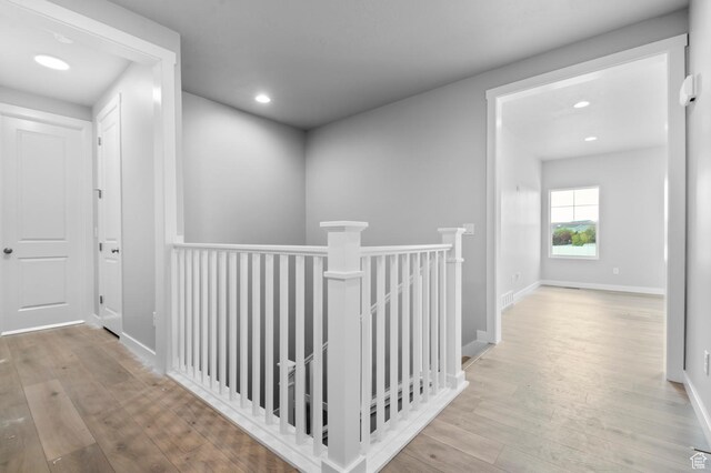 corridor with an upstairs landing, wood-type flooring, recessed lighting, and baseboards