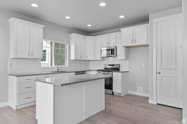 kitchen featuring stainless steel appliances, a sink, light wood finished floors, white cabinetry, and recessed lighting