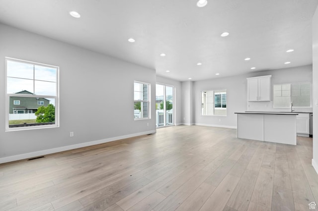 unfurnished living room with baseboards, recessed lighting, and light wood-style floors